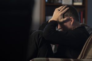 man with head in hands feeling depressed